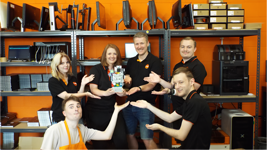 6 team members from furbd grouped together holding a trophy infront of shelves filled with computers and IPads